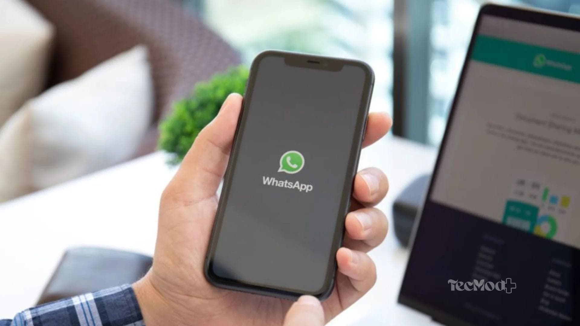 Pessoa usando whatsapp com computador ao fundo.